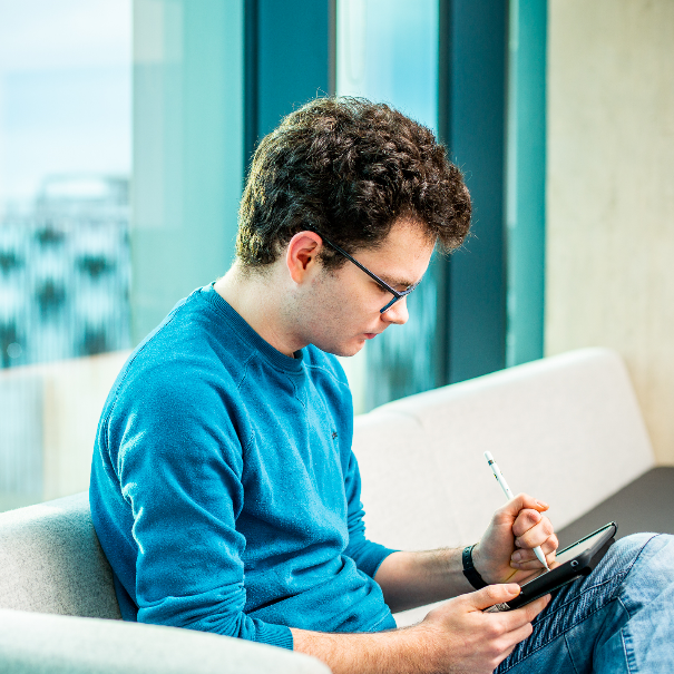 student sat on a sofa drawing on a tablet