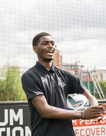sport student holding a football clapping on a 5 a side pitch
