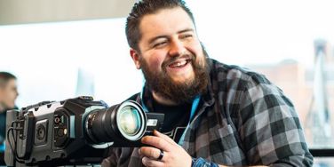 student stood with camera preparing to film 
