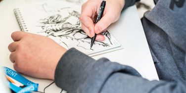 student drawing in notebook at a desk 