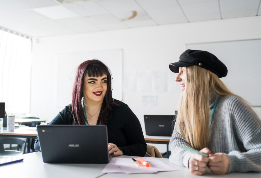Two students sat at a desk talking