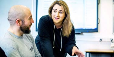 tutor leant over a table speaking to a student