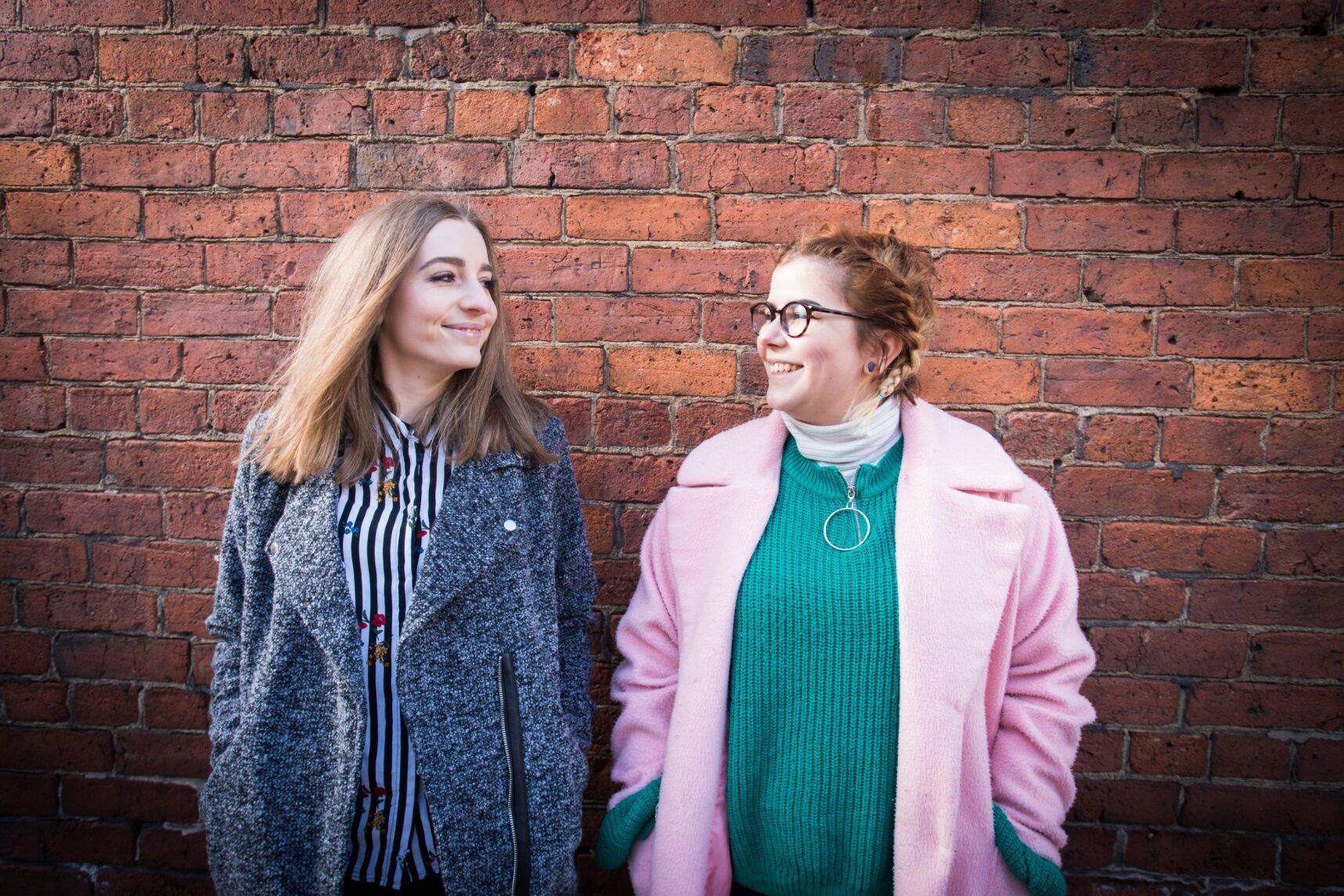 two people in front of a red brick wall