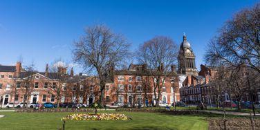 red brick buildings, with a green and trees in front