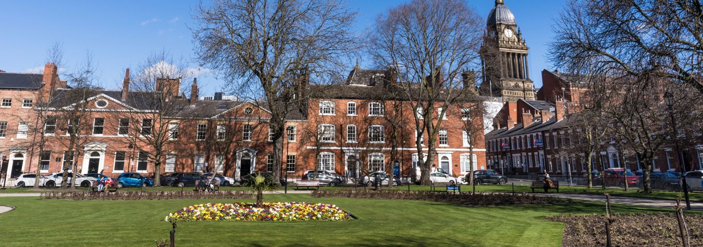red brick buildings, with a green and trees in front