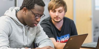 Students look down at a chromebook