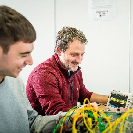 student and teacher stood over some electronics