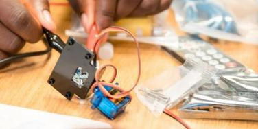 hands touching a servo motor with crocodile clips